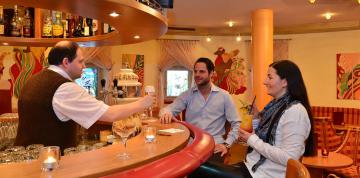 	Camarero y huéspedes en el bar del hotel IFA Alpenhof Wildental	